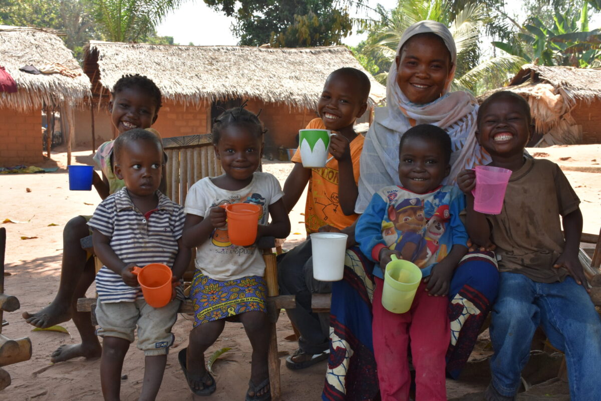 A woman and a group of children holding water cups, smiling.