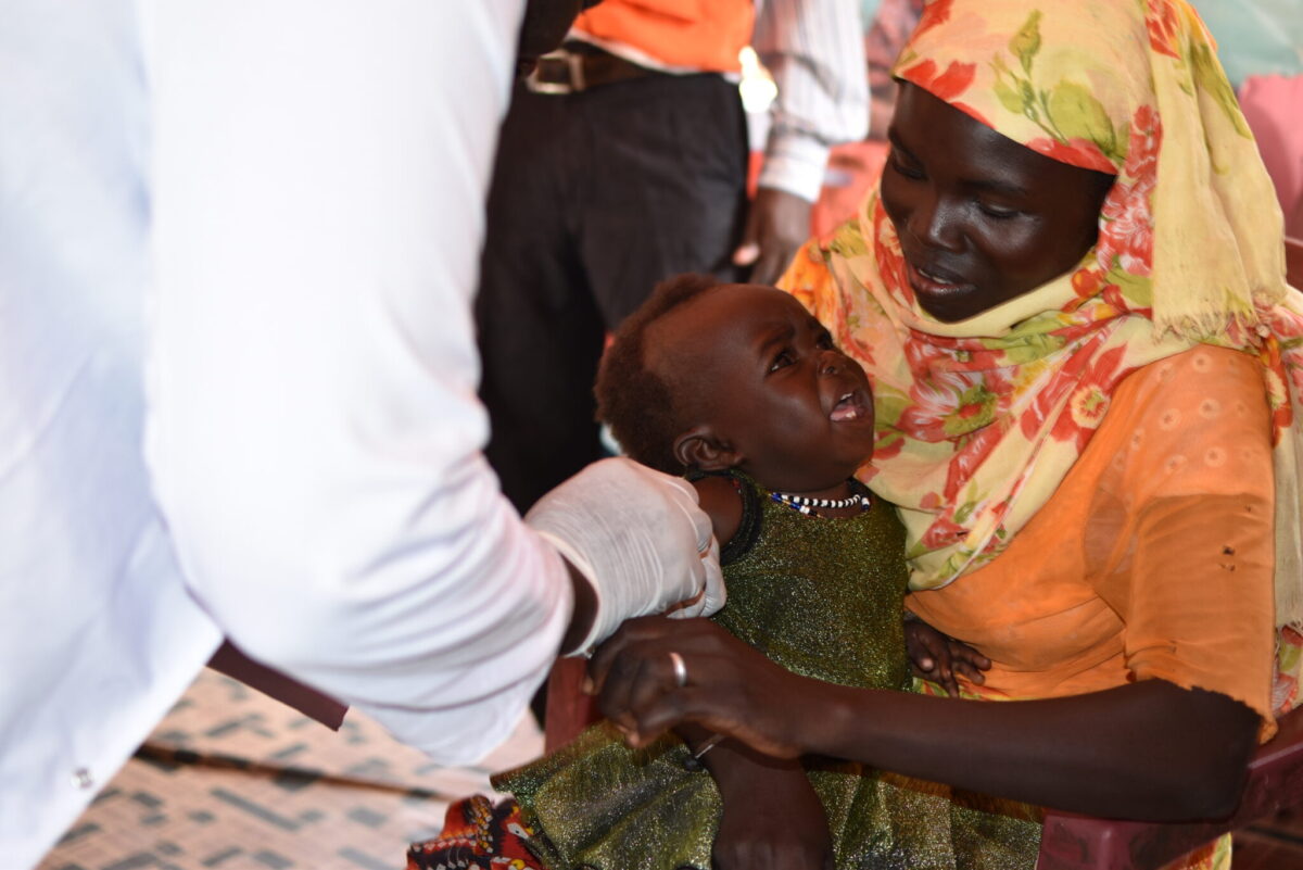 A woman holding a baby girl. The girl is getting vaccination.