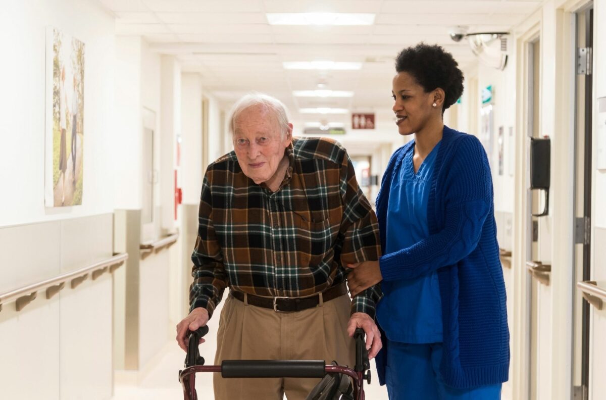Bruyère staff member helps gentleman down the hall