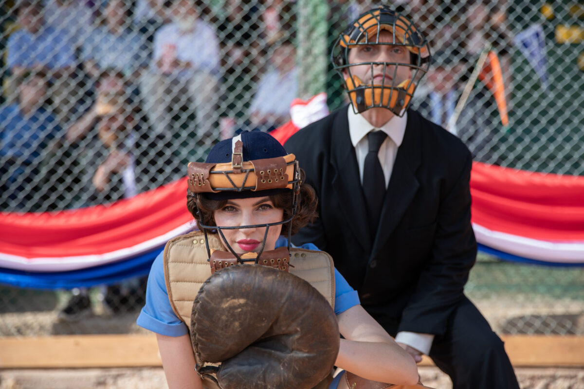 Une receveuse de baseball s'accroupit devant un arbitre pendant un match.